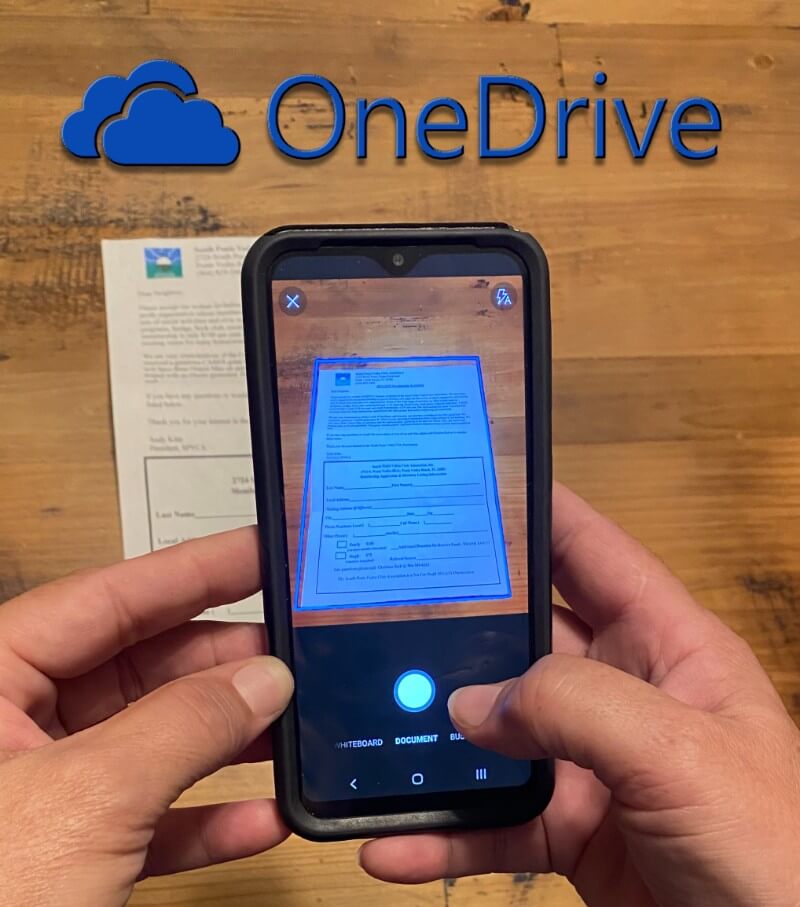 Hands holding a smart phone using OneDrive scanner.